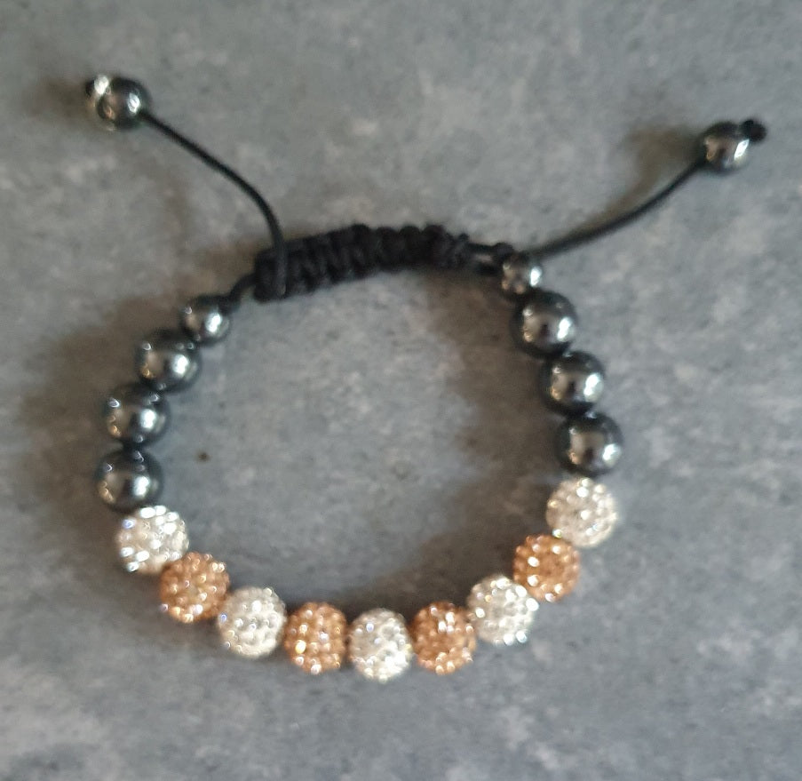 Beaded bracelet with black, white, and gold beads on a gray surface