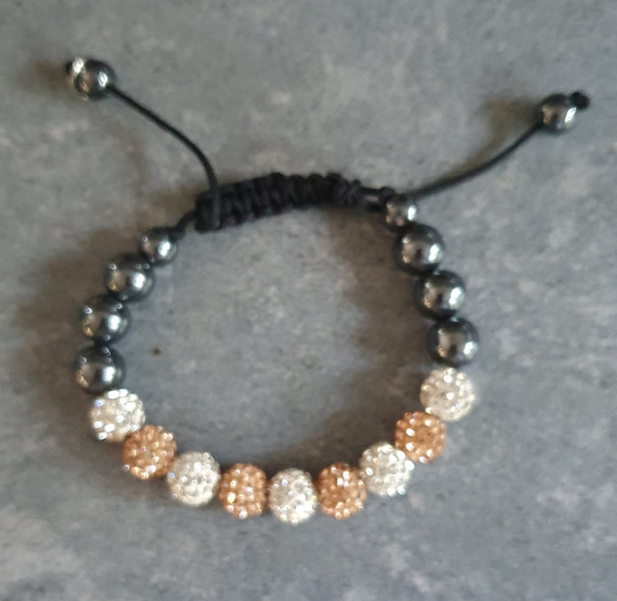 Beaded bracelet with black, white, and gold beads on a gray surface