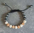 Beaded bracelet with black, white, and gold beads on a gray surface