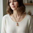 Woman wearing copper pearl and gold filigree cage pendant necklace