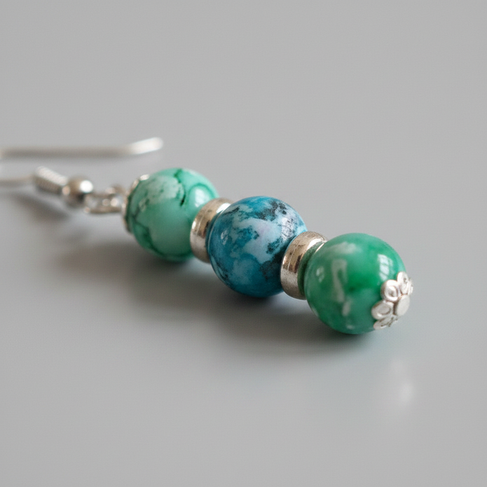 Close-up of turquoise and green marbled drop earrings with silver spacer rings