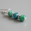 Close-up of turquoise and green marbled drop earrings with silver spacer rings