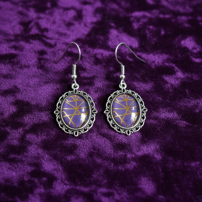 Gothic purple glass earrings flat lay on dark velvet