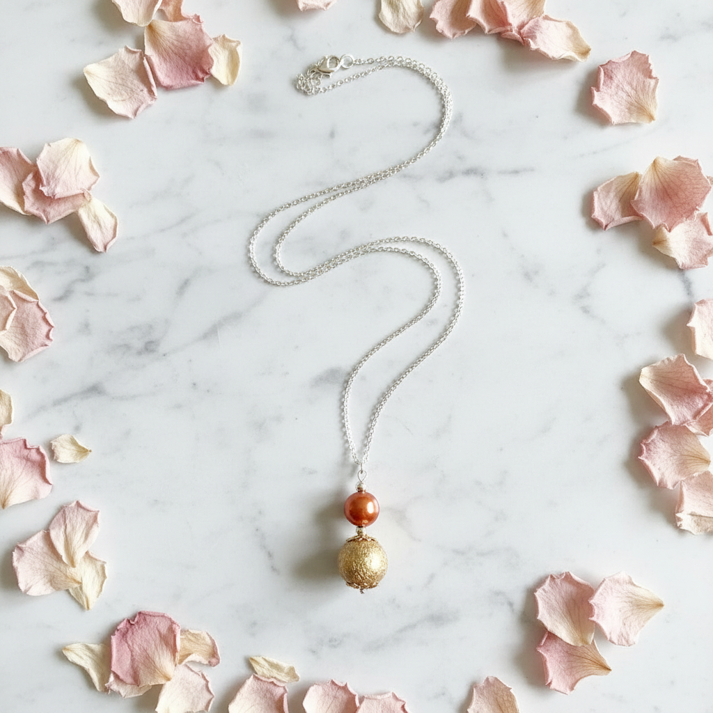 Copper pearl and gold textured ball pendant necklace flat lay with flower petals