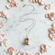 Copper pearl and gold textured ball pendant necklace flat lay with flower petals