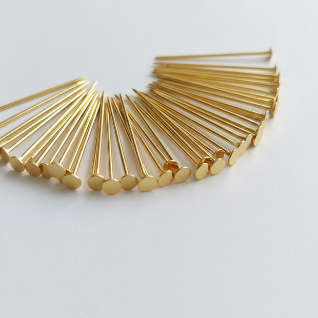 Gold coloured headpins fanned out showing flat head and pointed tip detail