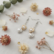 Double heart pearl drop earrings flat lay on white linen with dried flowers – handmade June birthday gift