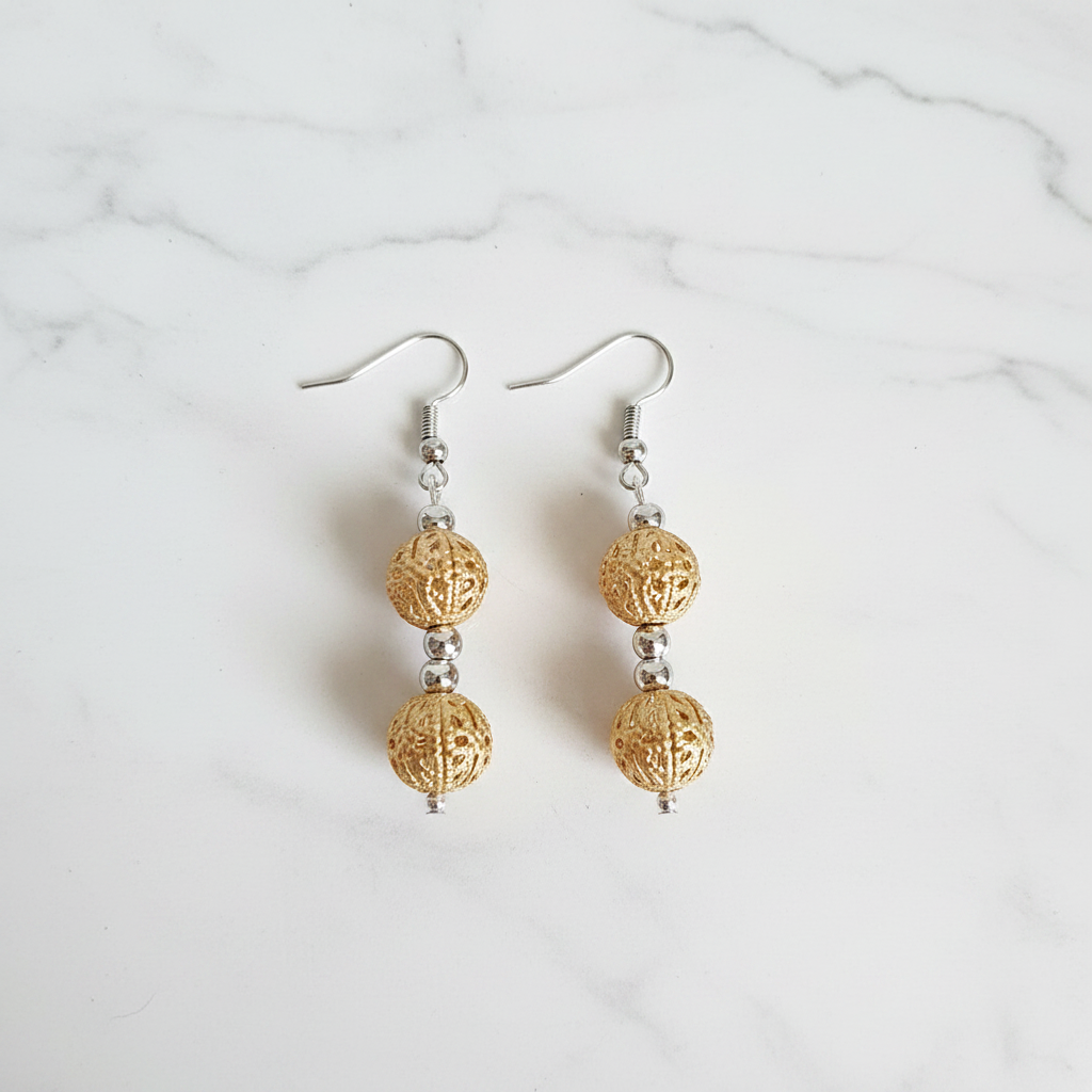Gold filigree double cage bead drop earrings flat lay on white marble