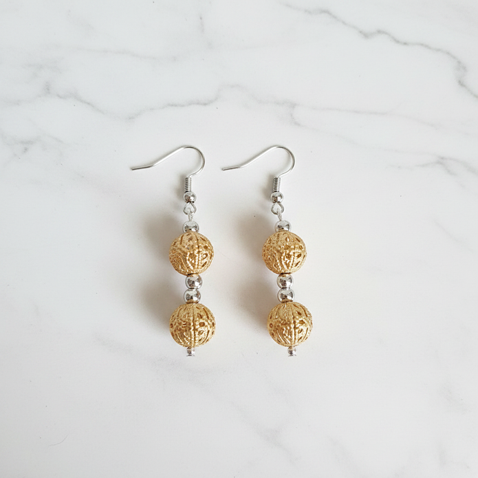 Gold filigree double cage bead drop earrings flat lay on white marble