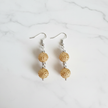 Gold filigree double cage bead drop earrings flat lay on white marble