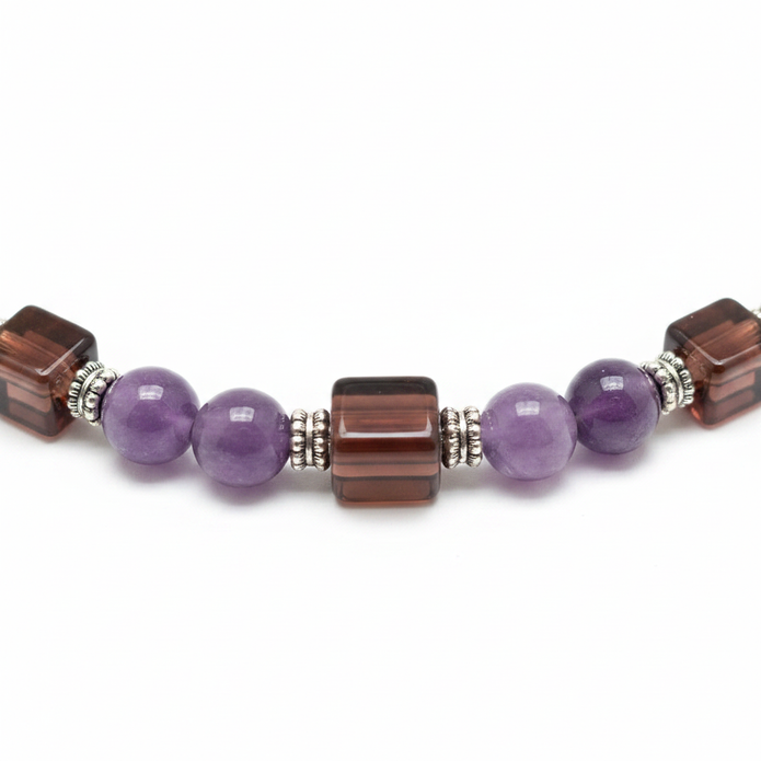 Close up detail of round and square purple and brown beads with silver spacers