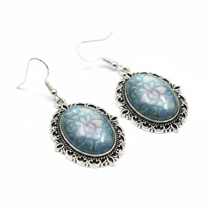 Close-up detail of iridescent blue-grey holographic cabochon and silver filigree earrings