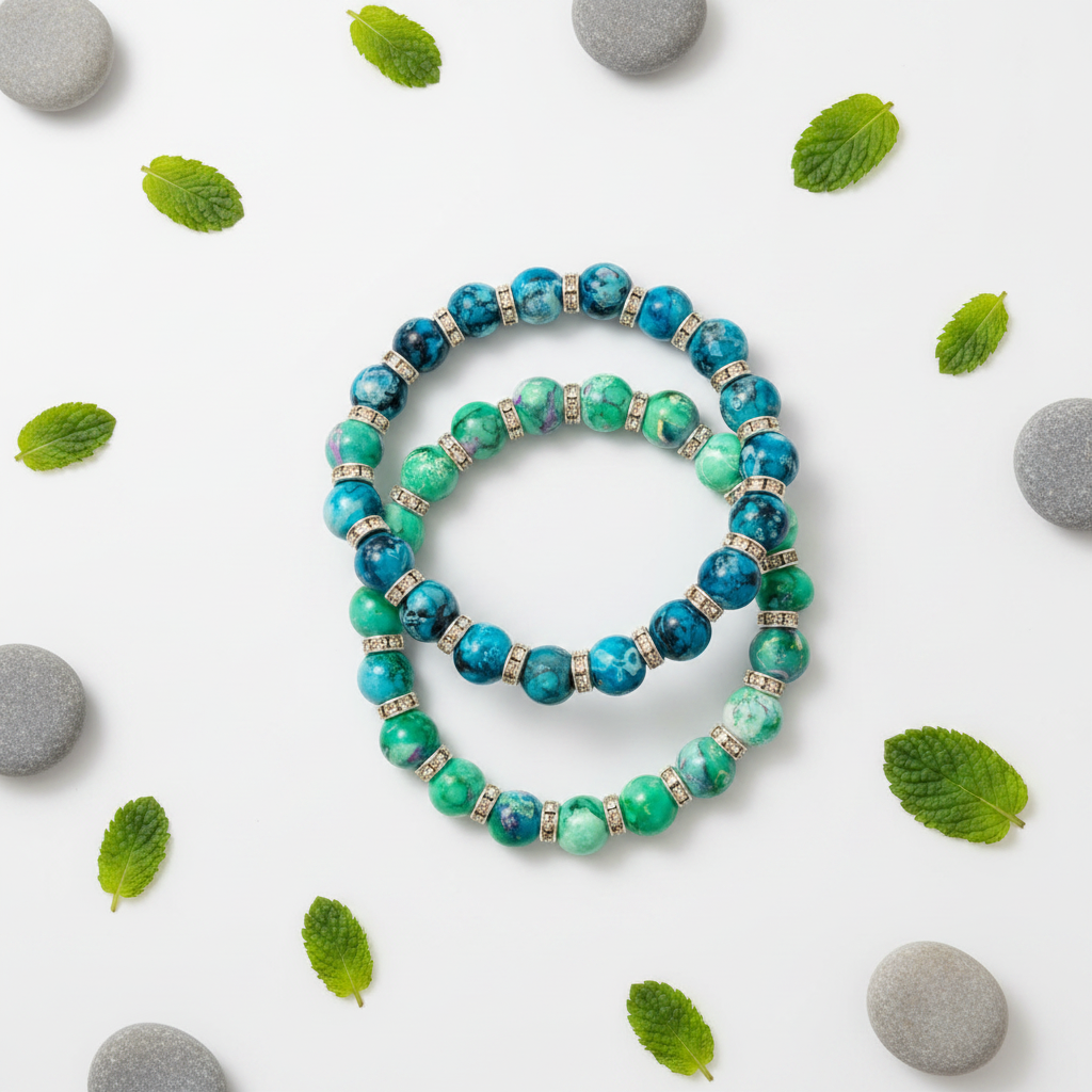 Flat lay of two turquoise and green marbled beaded bracelets with leaf and pebble props