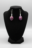 Rescued plum drop earrings displayed on earring stand