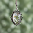 Close-up detail of small botanical cabochon drop earrings showing silver filigree metalwork