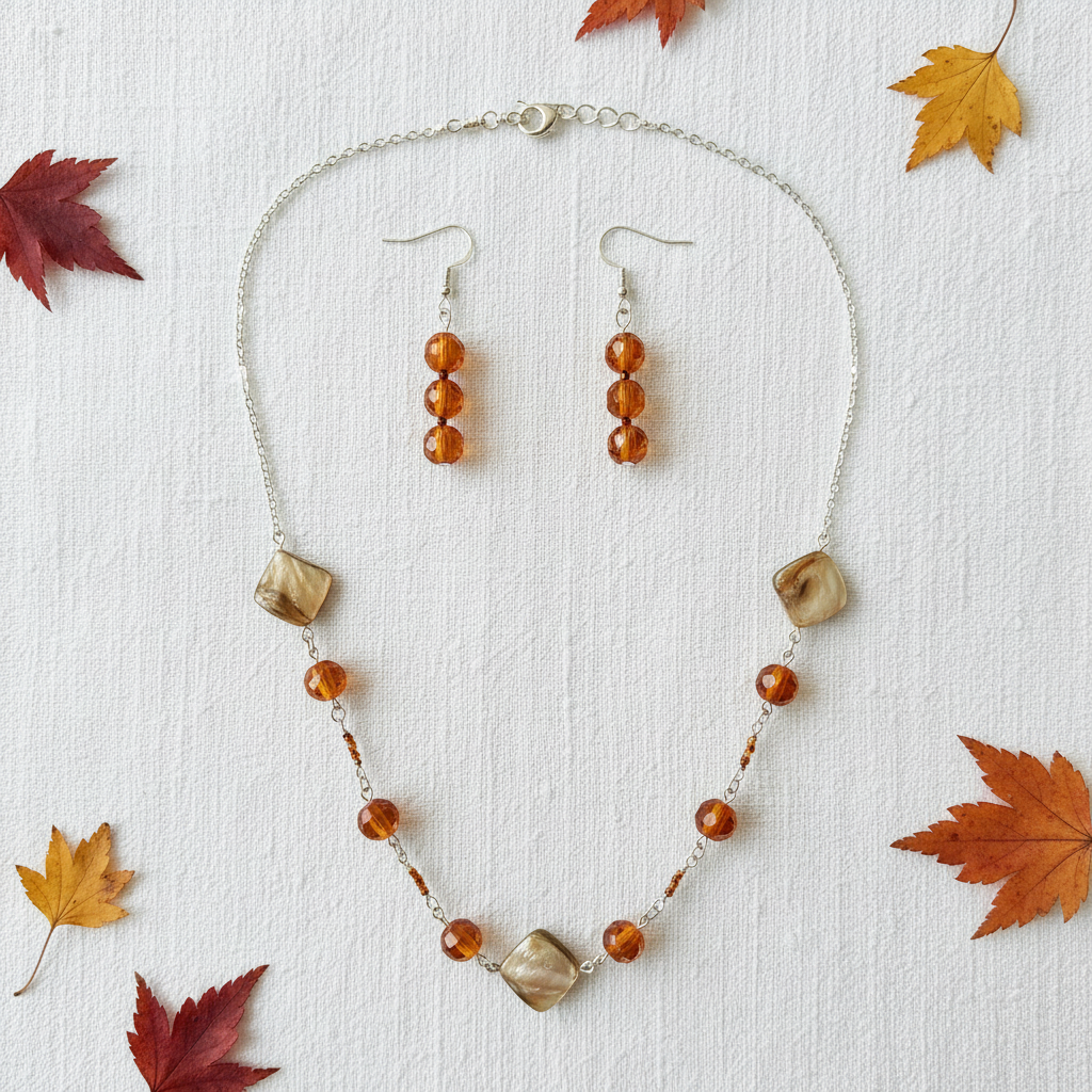 Flat lay of amber orange and gold beaded necklace and earrings set with autumn leaf props