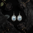 Iridescent rose and spiderweb cabochon drop earrings on black velvet with dark roses and gothic lace