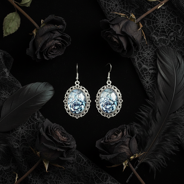 Iridescent rose and spiderweb cabochon drop earrings on black velvet with dark roses and gothic lace