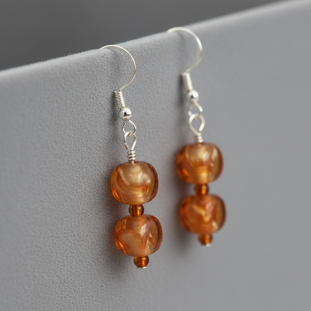 Close-up of amber orange and gold drop earrings on silver hooks