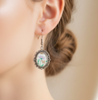 Lavender floral cabochon drop earrings worn on model's ear, lifestyle shot