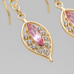 Close-up macro of gold plated filigree leaf drop earrings showing pink marquise crystal and diamante detail