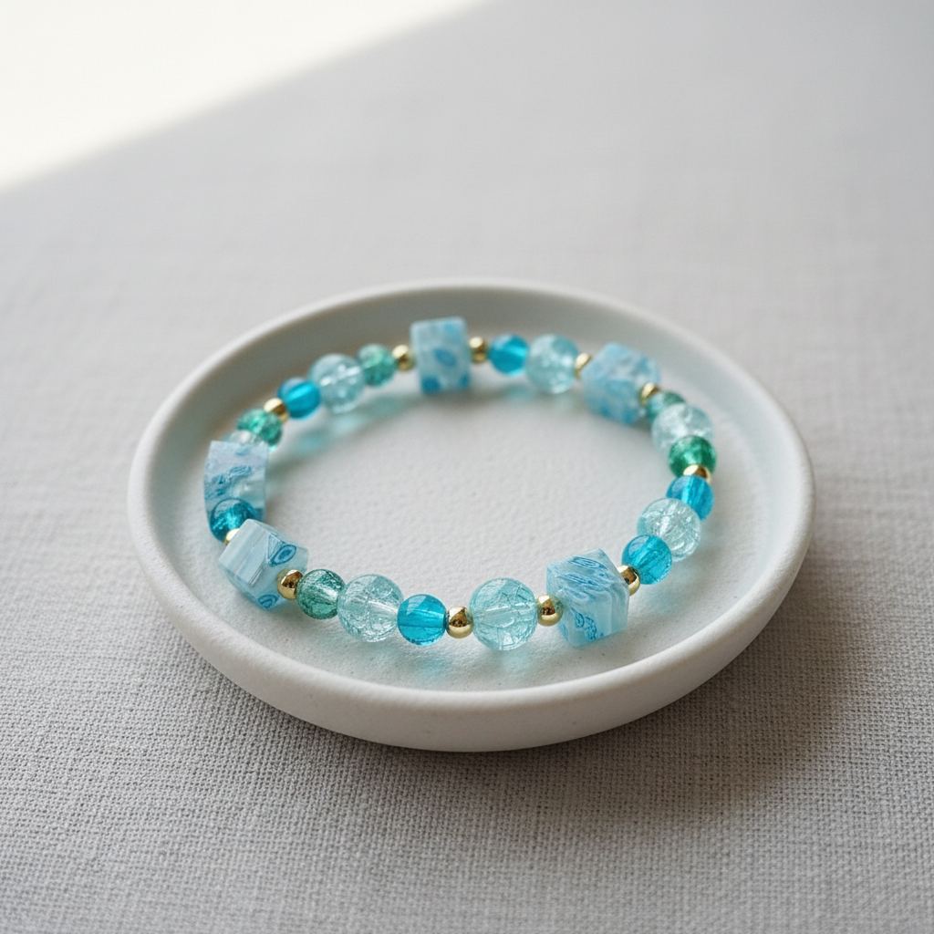 Teal crackle bead bracelet displayed on a white ceramic jewellery dish