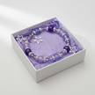 Purple and lilac star charm bracelet in a white gift box with purple tissue paper