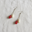 Red and cream oval bead drop earrings flat lay on white linen surface