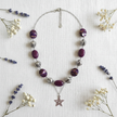 Rescued plum bead necklace with star pendant flat lay with dried flowers