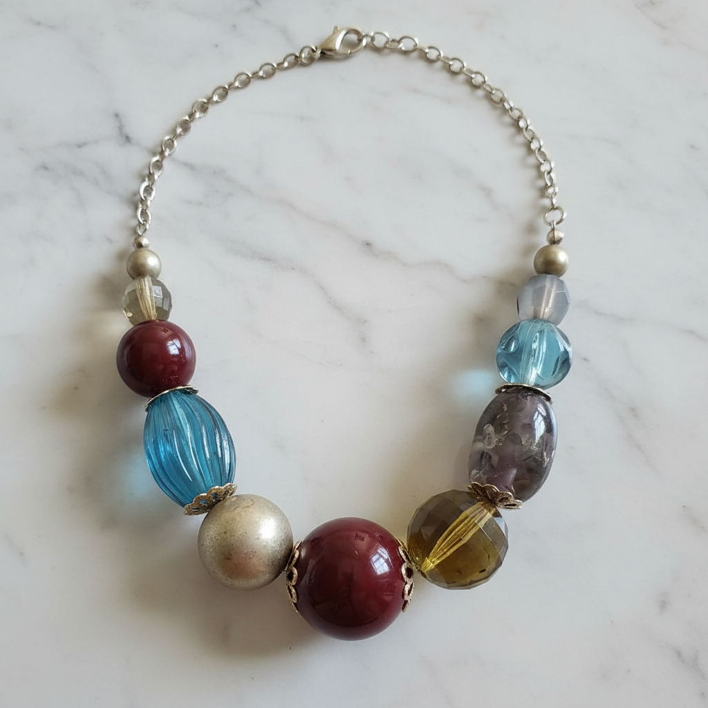 Rescued & Remade chunky mixed bead statement necklace draped on white marble with natural light