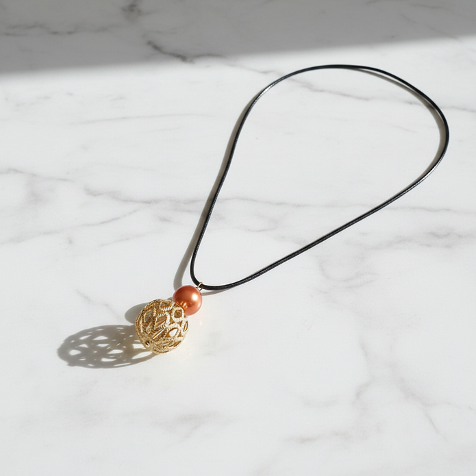 Copper pearl and gold filigree cage pendant necklace flat lay on white marble