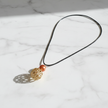 Copper pearl and gold filigree cage pendant necklace flat lay on white marble