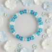 Turquoise and white beaded bracelet flat lay with scattered flower petals