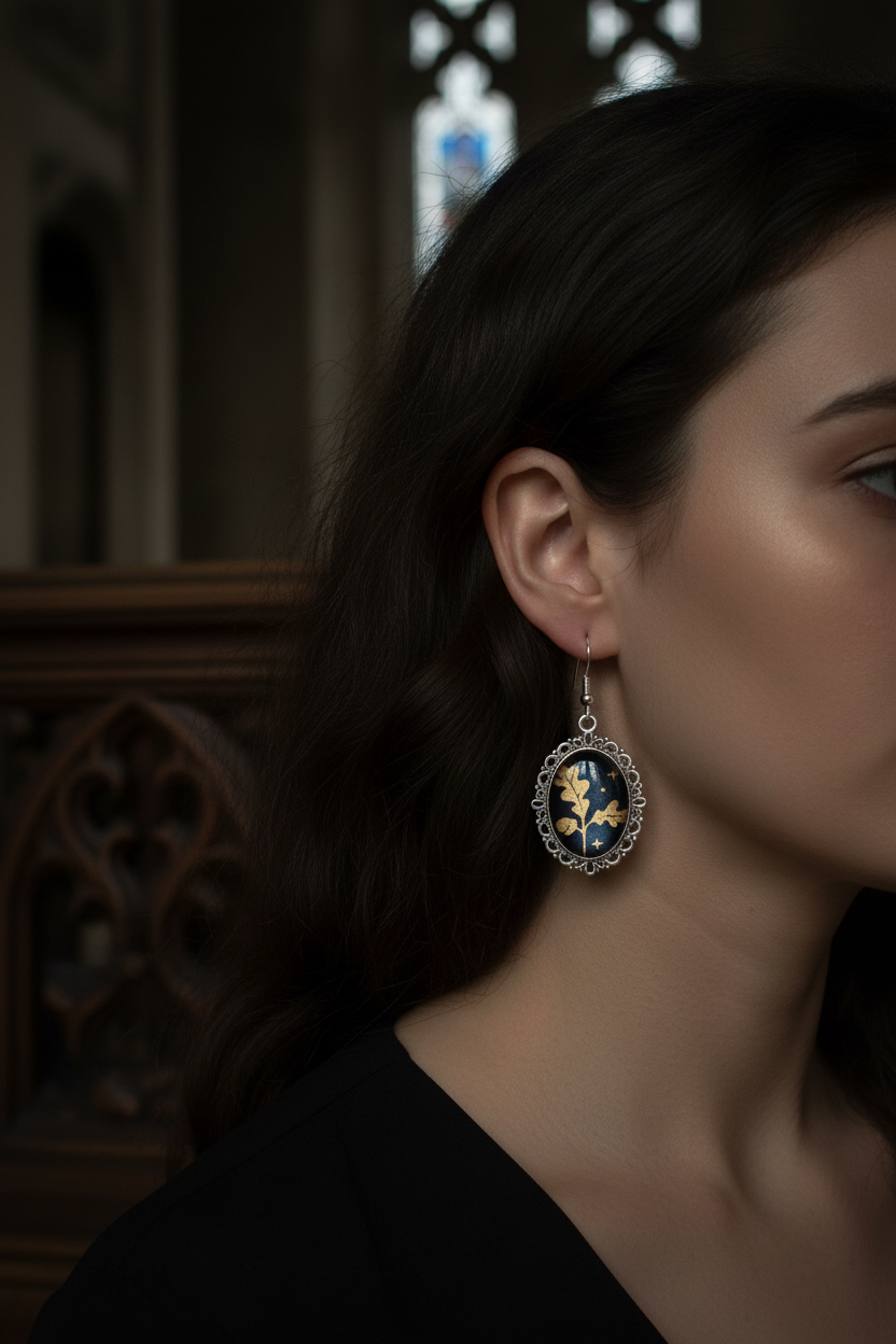 Model wearing gold oak leaf cabochon drop earrings with moody gothic background
