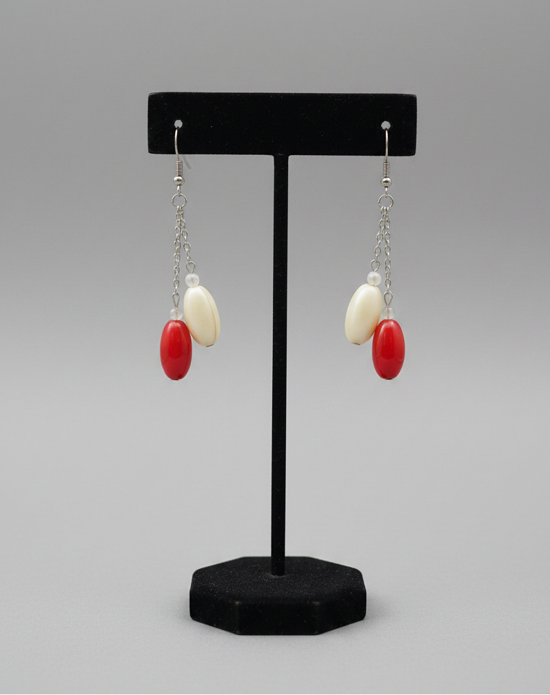 Close-up detail of red and cream oval bead drop earrings showing bead texture and chain