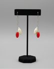 Close-up detail of red and cream oval bead drop earrings showing bead texture and chain