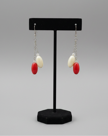 Close-up detail of red and cream oval bead drop earrings showing bead texture and chain