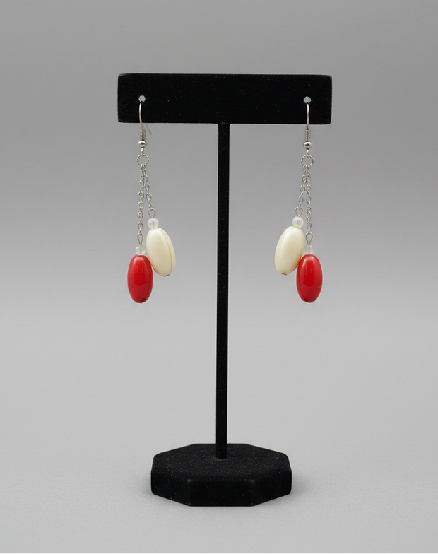 Close-up detail of red and cream oval bead drop earrings showing bead texture and chain