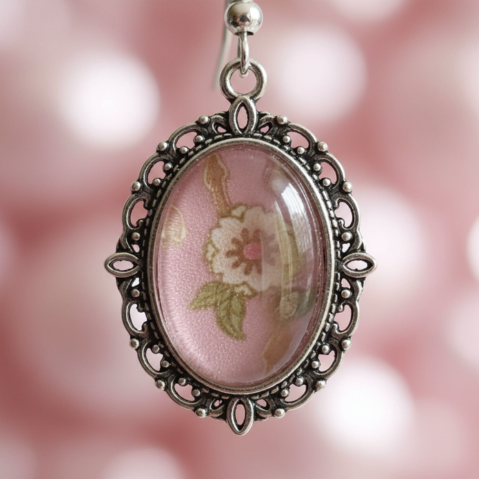 Close-up detail of pink floral cabochon drop earrings showing filigree metalwork