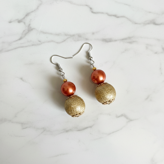 Copper pearl and gold textured bead drop earrings flat lay on white marble