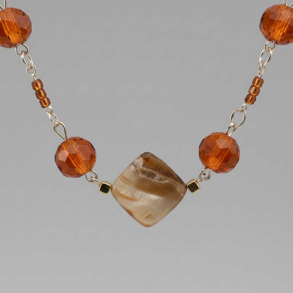 Macro close-up of amber orange and gold cube beads on silver chain necklace