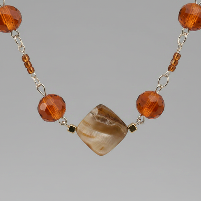 Macro close-up of amber orange and gold cube beads on silver chain necklace