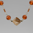 Macro close-up of amber orange and gold cube beads on silver chain necklace