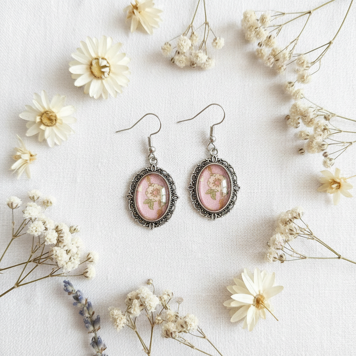 Pink floral cabochon drop earrings flat lay on white linen with dried flowers