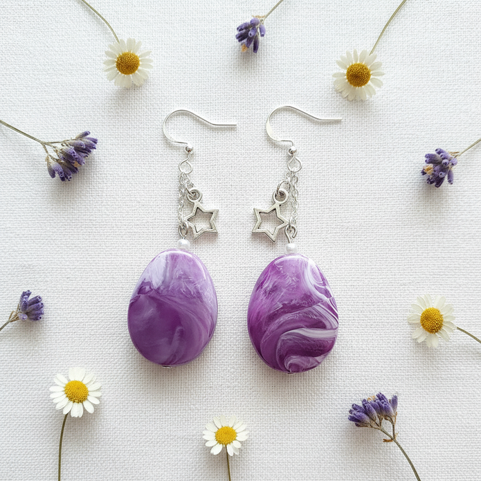 Rescued and remade purple marbled star charm earrings flat lay with dried flowers