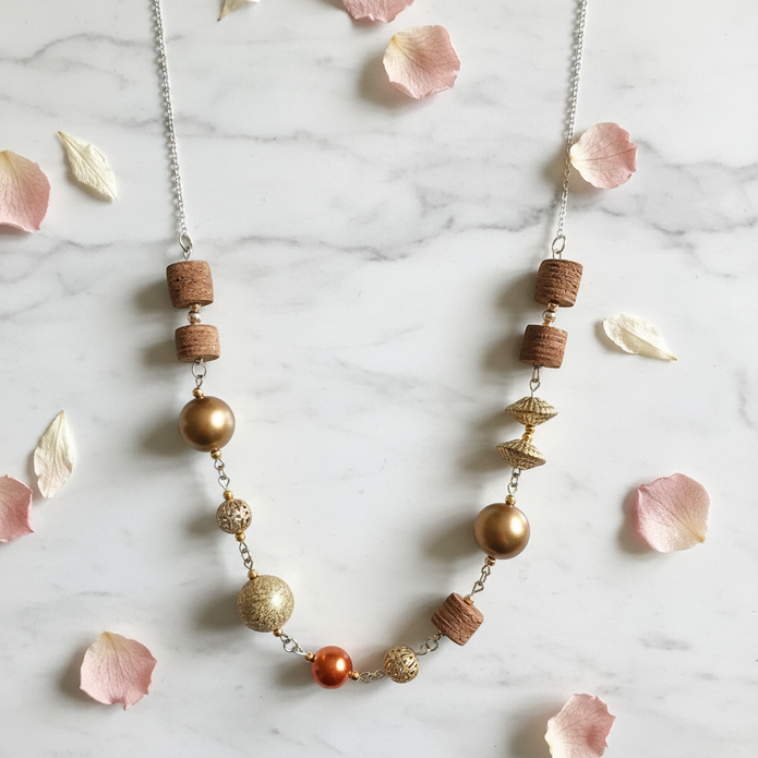 Gold and copper mixed bead statement necklace flat lay with flower petals