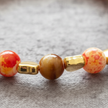 Close-up detail of orange marbled beads and gold heart spacers on elasticated bracelet