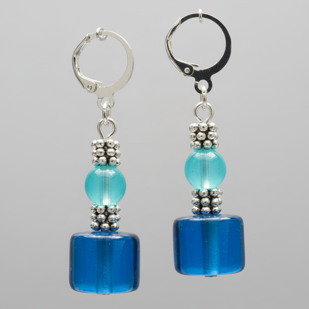 Macro close-up of blue glass cube and aqua bead drop earrings with silver daisy spacers