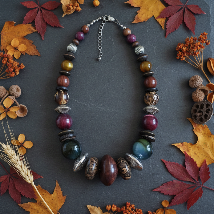 Rescued & Remade jewel tone necklace draped on dark slate with autumn leaves and botanicals
