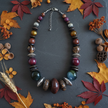 Rescued & Remade jewel tone necklace draped on dark slate with autumn leaves and botanicals